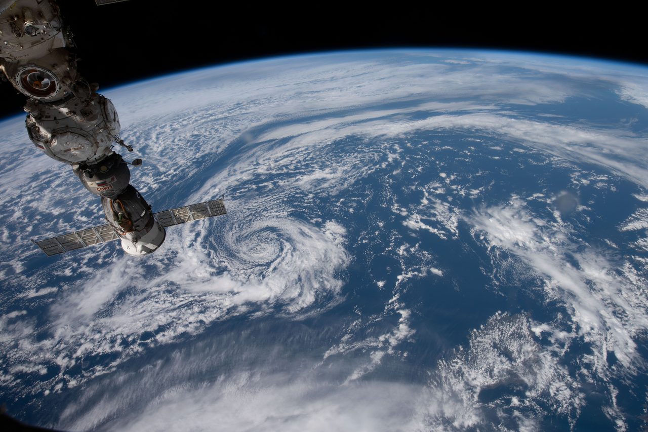 Part of the International Space Station in orbit above a partly cloudy Pacific Ocean