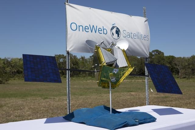 Aerial view of groundbreaking ceremony for One Web Satellites with attendees and construction equipment.