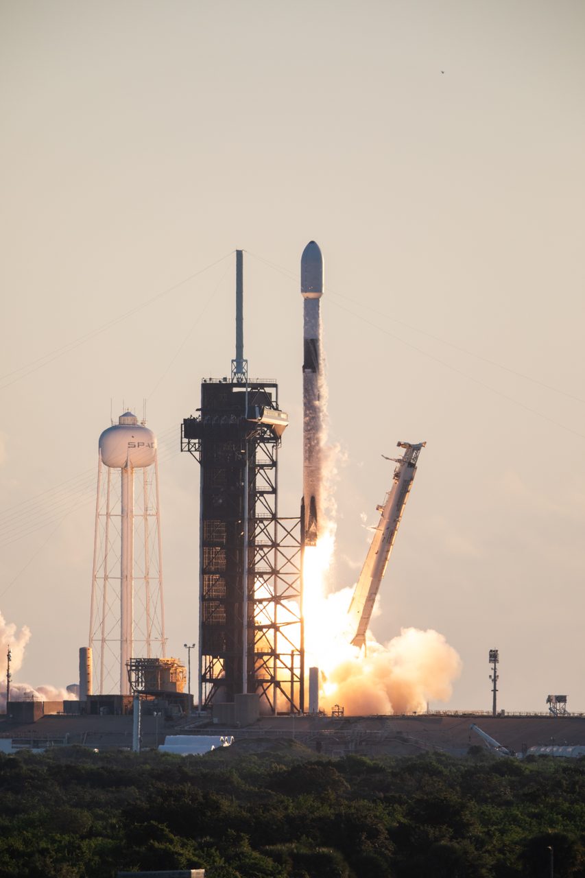A rocket launching into a clear blue sky with a trail of smoke.