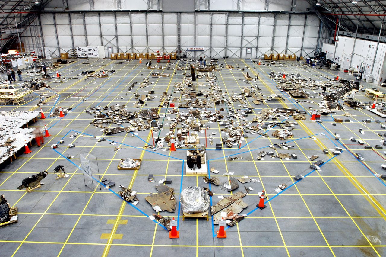 Columbia debris hangar at Kennedy Space Center showing orbiter outline and recovered pieces.