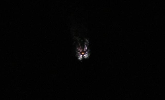 SpaceX Falcon Heavy rocket launching at night with fiery exhaust against a starry sky