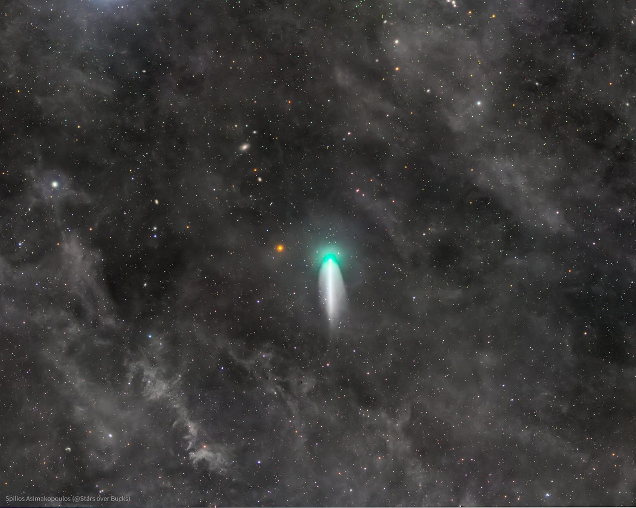 A bright comet 220P with a glowing tail streaks across a star-filled night sky.