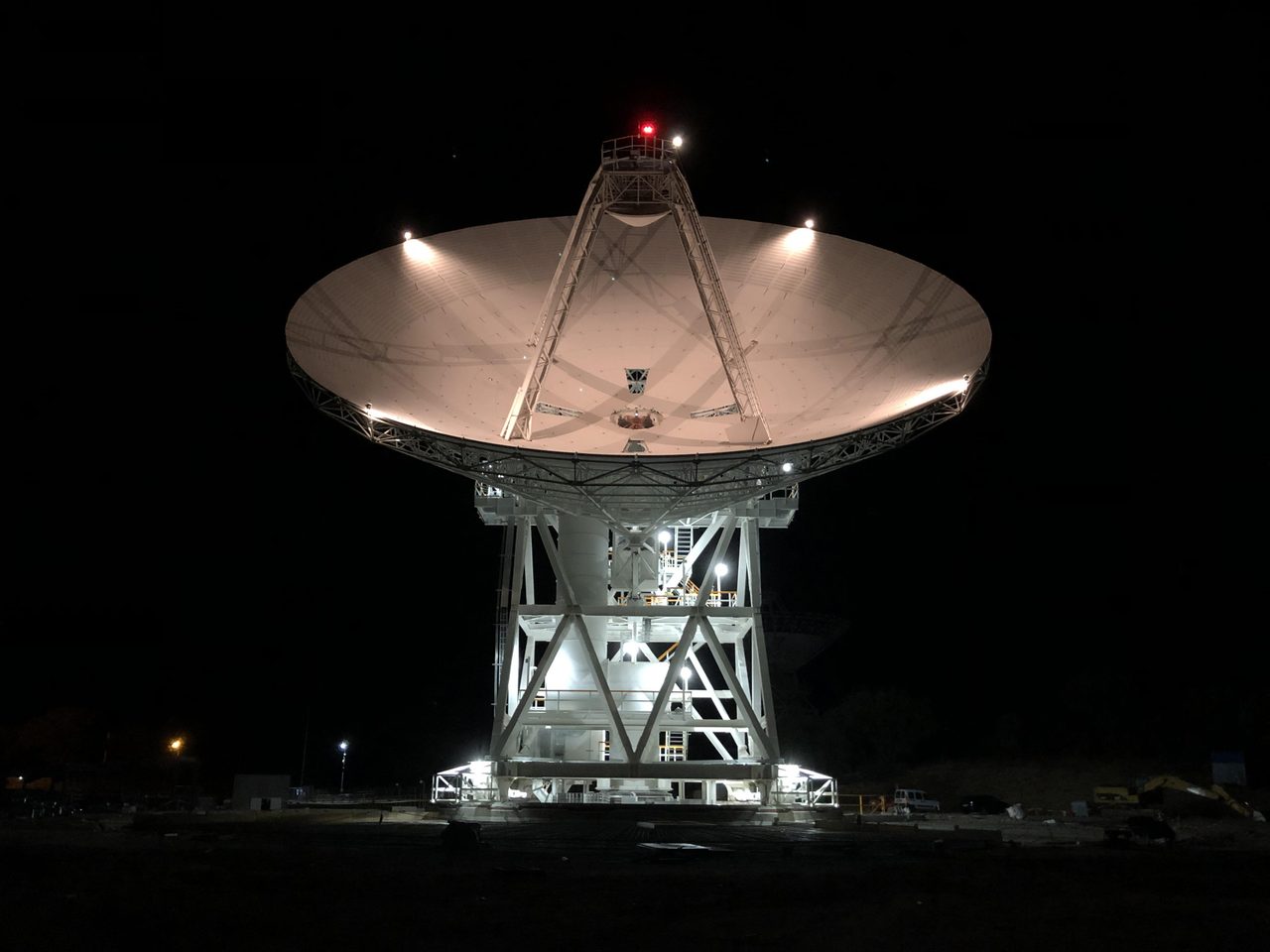 A Deep Space Network antenna dish lit up at night