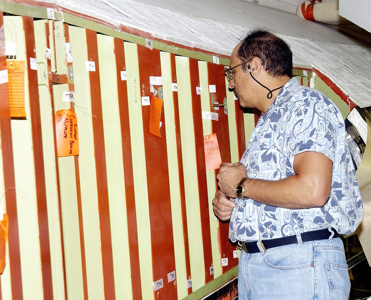 Technician inspecting Space Shuttle Atlantis wing attachment points for reinforced carbon-carbon panels at Kennedy Space Center.