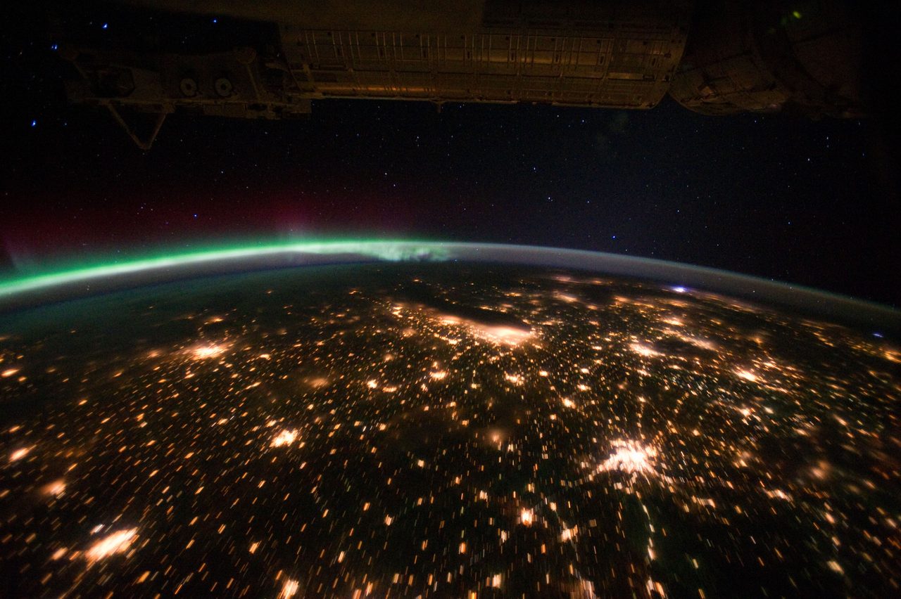 Aurora Borealis glowing above city lights on horizon, captured by Expedition 29 crew.