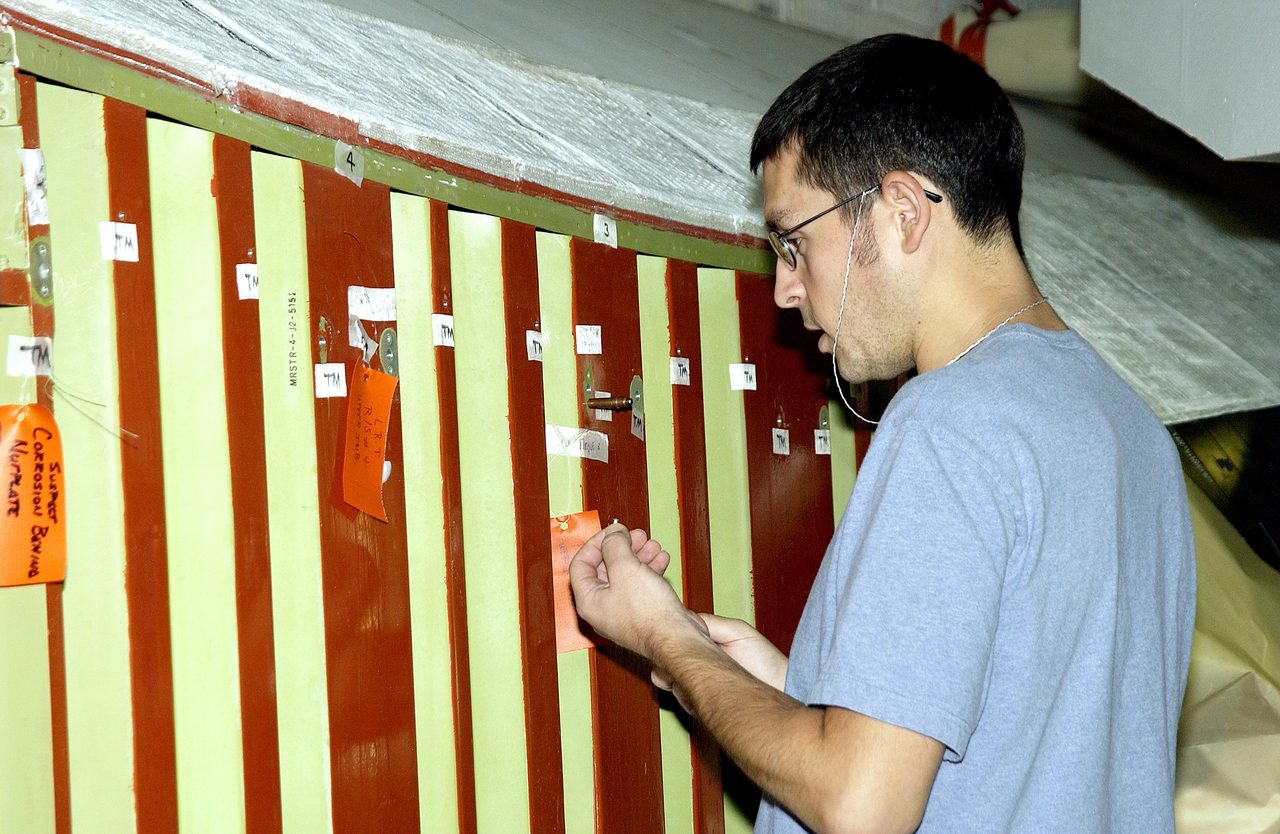 Technician inspects Space Shuttle Atlantis wing's attachment points in Orbiter Processing Facility at Kennedy Space Center.