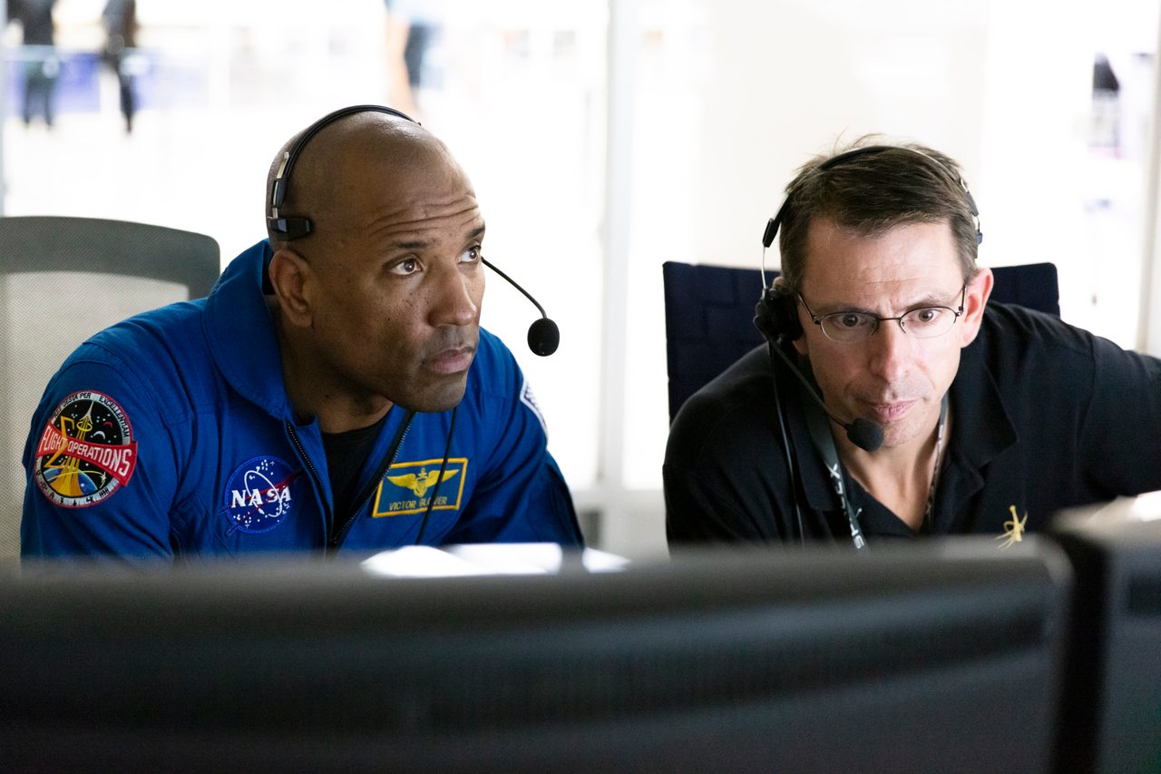Astronauts observe SpaceX Crew Dragon's static fire test, standing near the launch pad with anticipation.